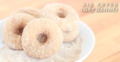 three sugared donuts in a white bowl on a wooden table with the words air fryer cake donuts