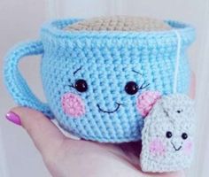 a crocheted coffee cup with a smiling face on it and a small stuffed animal