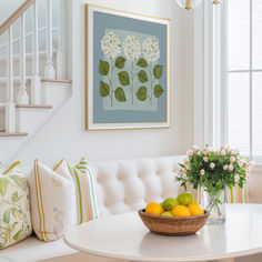 a bowl of fruit sitting on top of a table next to a white couch in a living room