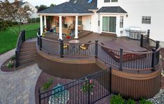 an outdoor deck with stairs and railings next to a house