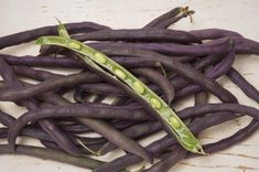 purple beans with green tops on a wooden surface