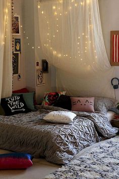 two beds in a room with white curtains and lights on the wall above them,