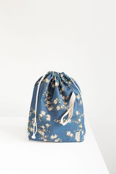 a blue flowered bag sitting on top of a white table next to a wall