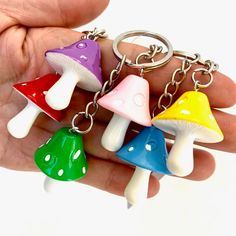 four different colored mushrooms on a keychain being held by a person's hand