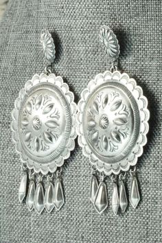 These sterling silver earrings were made by Navajo silversmith Terry Charlie. The back of the earrings are signed T. Charlie and stamped sterling.Length: 2 7/8"Width: 1 5/8"Free shipping on all orders! We ship with USPS and always include tracking. All orders ship within a day of payment.Returns are accepted up to 30 days after you receive your order. Just send us a message. Our shop offers cash back or store credit. The item must be returned in new condition. Elegant Silver Concho Earrings, Silver Dangle Earrings With Concho, Silver Concho Drop Earrings, Silver Concho Dangle Earrings, Southwestern Silver Concho Earrings, Vintage Sterling Silver Etched Earrings, Vintage Etched Sterling Silver Earrings, Traditional Silver Concho Jewelry, Native American Jewelry