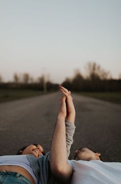 two people laying down on the road with their hands in the air