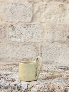 a white cup sitting on top of a stone wall