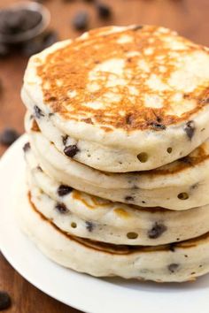 a stack of pancakes sitting on top of a white plate next to chocolate chips and coffee beans