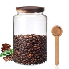 a glass jar filled with coffee beans next to a wooden spoon