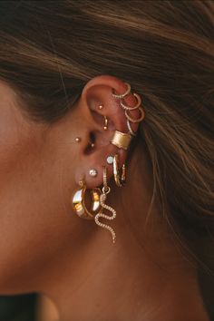 a close up of a woman's ear with three different types of earrings on it