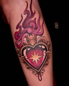 a heart tattoo with flames and a star on the inside of its center piece is shown