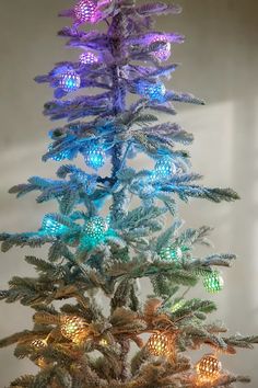 an artificial christmas tree is lit up with colored lights and pineconi cones on the branches