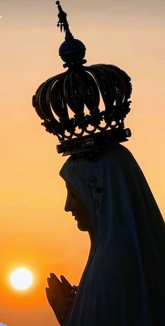 a statue with a crown on top of it's head in front of the sun