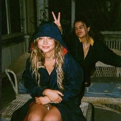 two women sitting on a bench with one giving the peace sign