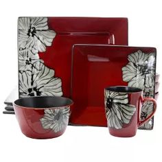 a set of red and black dinnerware with white flowers on the plates, cups and saucers