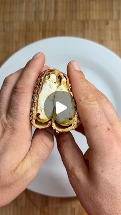 a person is holding an egg sandwich on a plate