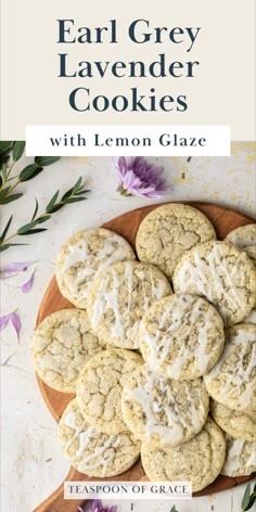 a plate full of lemon glaze cookies on top of a wooden cutting board with flowers in the background