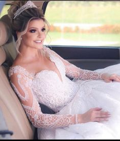 a woman sitting in the back seat of a car wearing a wedding dress and tiara