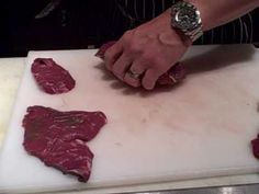 a man is cutting up raw meat on a cutting board