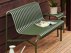 a green bench sitting on top of a wooden deck next to a potted plant