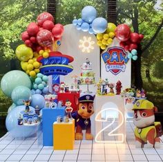 a birthday party with balloons and toys on the table in front of an image of paw patrol