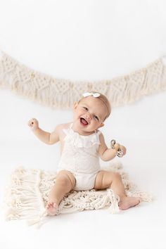 a baby is sitting on a blanket and holding a rattler in her right hand