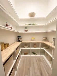 an empty kitchen with white shelves and wooden flooring on the walls, in front of a skylight