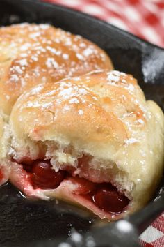 two pastries in a cast iron skillet on a table with red and white checkered cloth