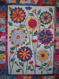 a quilted wall hanging with colorful flowers on it