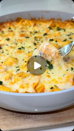 a casserole dish with cheese and spinach being spooned into the casserole