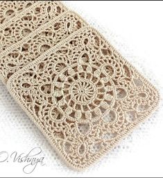 a crocheted cell phone case sitting on top of a white surface with an intricate design