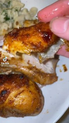 a person is eating some meat on a plate with potatoes and broccoli in the background