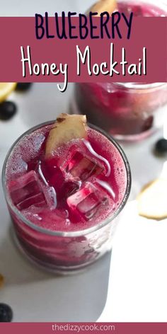 two glasses filled with blueberry honey mocke cocktail on top of a white table