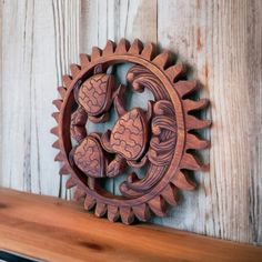 a decorative wooden object on top of a wood shelf in front of a white painted wall