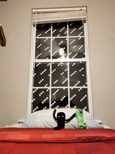 a bed in front of a window with a black and white pattern on the wall