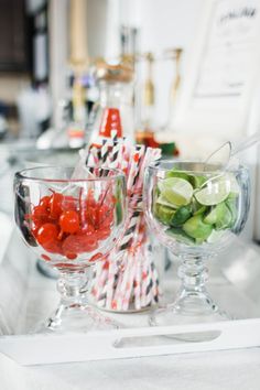 three glasses filled with different types of fruit on a tray next to another glass bowl