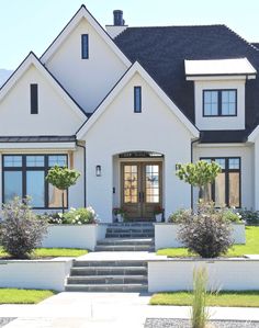 a white house with steps leading up to the front door and landscaping on both sides