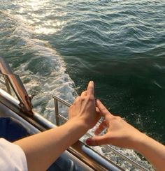 two hands reaching out towards the water from a boat