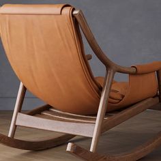 a wooden rocking chair with leather seat and back cushions on a wood floor in front of a gray wall