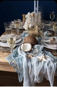 the table is set with plates, silverware and glassware for an ocean themed dinner