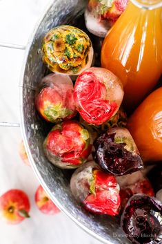 a bowl filled with fruit sitting on top of a white marble counter next to an orange juice bottle