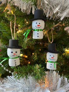 three snowman ornaments hanging from a christmas tree