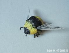 a yellow and black bee sitting on top of a white surface