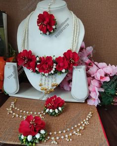 the necklace and earrings are decorated with red flowers, pearls, and pearls on display