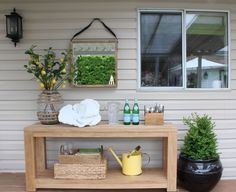 a wooden table sitting on top of a hard wood floor next to a window and potted plants