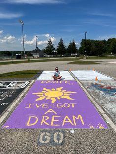 a person sitting on the ground in front of a sign that says live got a dream