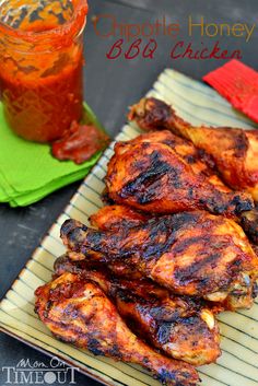 grilled chicken wings on a plate next to a jar of chili and ketchup