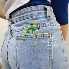 the back of a woman's jeans with flowers embroidered on it