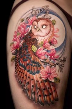 an owl and flower tattoo on the back of a woman's shoulder, with pink flowers