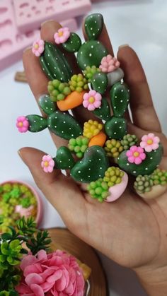 a hand holding a fake cactus with flowers on it